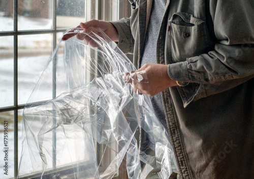 Male opens up plastic sheeting, used to insulate windows in winter time