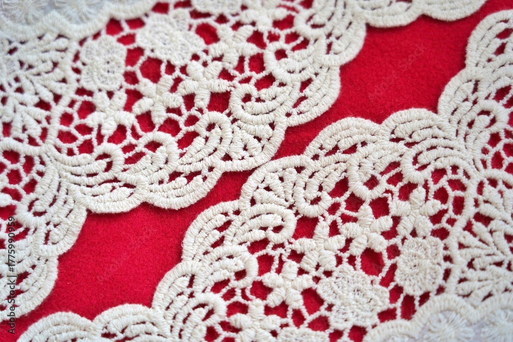 Obraz premium Curved scalloped lace patterns aligned with twin gaps of red background, creating a symmetrical and elegant textile layout