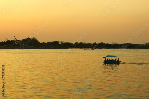 A Swan Paddle boat cruising on sunset sea from afar with scenic landscape