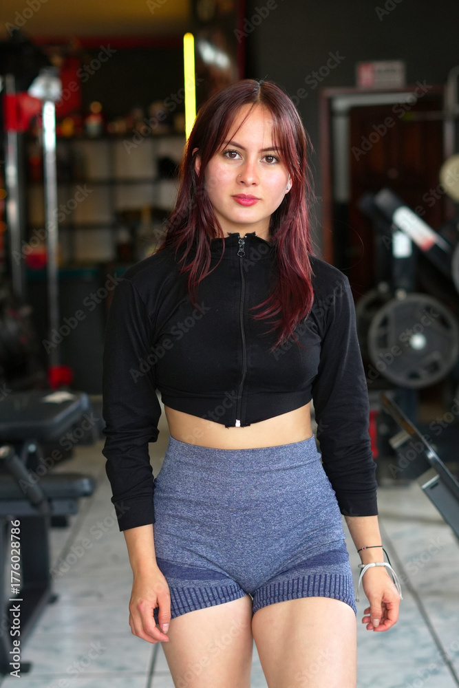 Fototapeta premium Young woman standing in gym creating fitness content