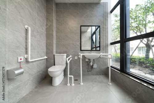 accessible bathroom with grab bars, large windows, and gray tiles