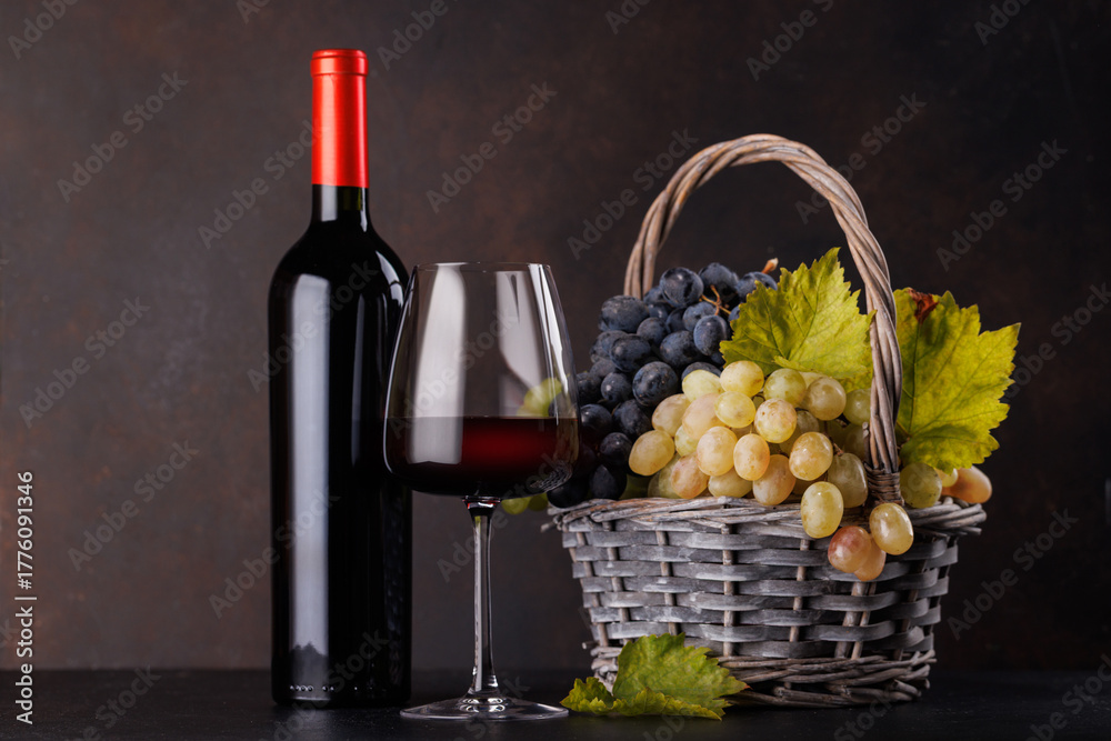 Naklejka premium Red wine bottle with a glass and basket of fresh grapes