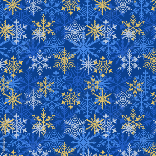 Seamless pattern of blue, white, and gold snowflakes on a dark blue background. Winter holiday design for wallpaper, wrapping paper, and textiles.
