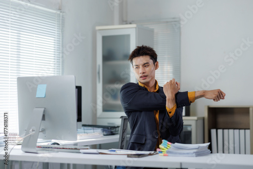 Businessman stretching arms at office desk for comfort