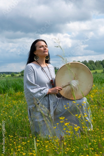 Portrait of a middle-aged shaman woman among yellow flowers