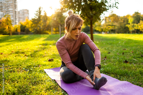 Fotografía Adult woman is is sitting on exercising mat in park in autumn