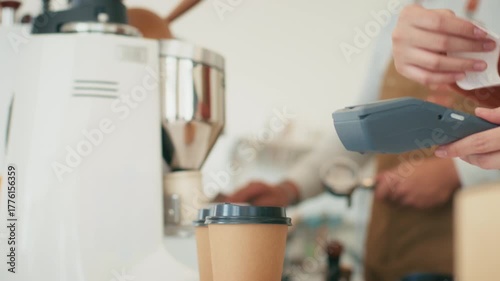 Close up of Customer hand using credit card tapping on Card Reader, terminal for making payment in coffee shop. Cashless and Contactless payment buying drink, making payment transaction to cashier.