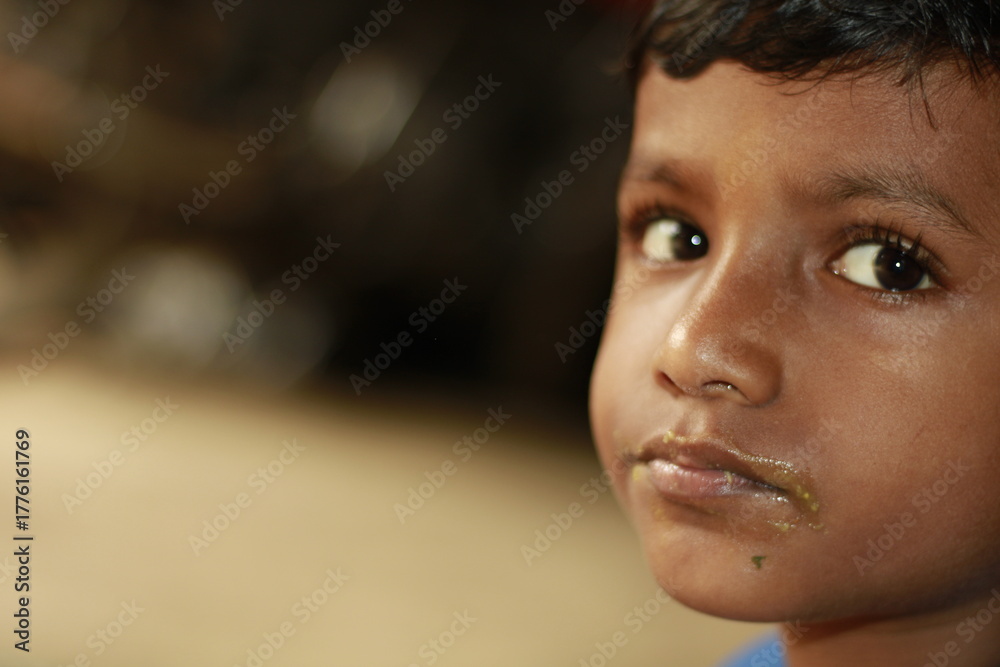 Φωτογραφία Close-up view of a young child eating homemade food, with small bits of food around the mouth,  innocence of childhood mealtime and the emotional bond of being lovingly fed by a caring hand