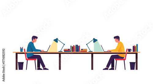 Two male colleagues working diligently at a shared long desk, each focused on their laptop with books and a lamp nearby.