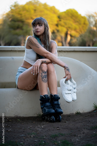 Woman with tattoos and inline skates relaxing outdoors