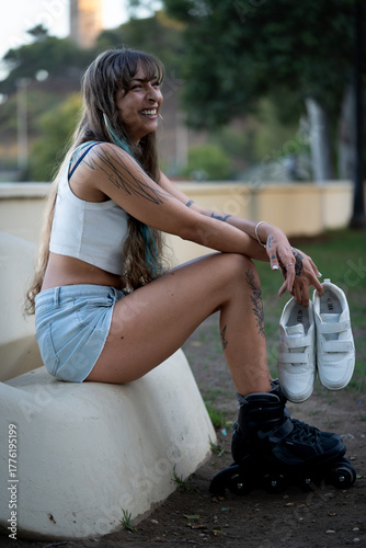 Young woman smiling holding sneakers after rollerblading