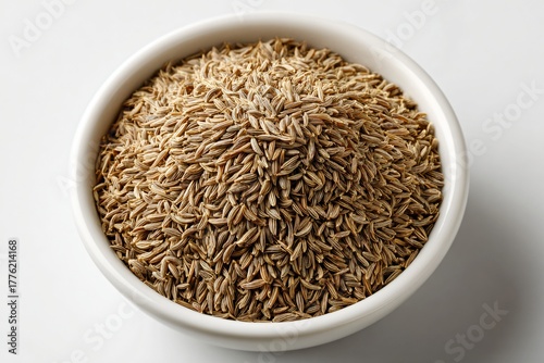 Close up of aromatic cumin seeds filling a white bowl on a white surface ready for cooking and adding flavor to food dishes
