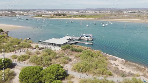 Scenic drone view of the ferry terminal on Tavira Island, Portugal, with boats, piers, and turquoise waters.