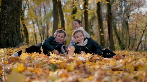 It is vibrant and cheerful. A few happy children are playing briskly, throwing leaves in the air, while others sit nearby, enjoying the rhythmic music coming from their phones.