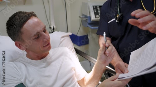 A man in hospital is signing a document with blood pressure monitoring. With a doctor 