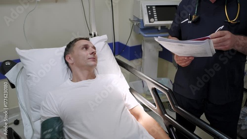 A patient lies in a hospital and currently undergoing blood pressure monitoring in a professional medical setting, with a doctor present. 