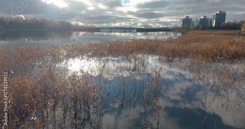 Fast drone flight over shimmering water surface in strong golden backlight