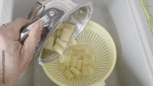 Draining Cooked Pasta into a Colander in Kitchen Sink