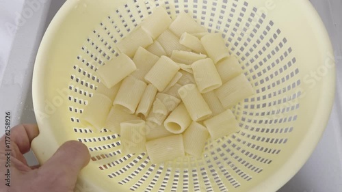 Draining Cooked Pasta into a Colander in Kitchen Sink