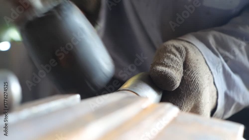Close up hands of blacksmith processing iron detail using hammer. Adult man in gloves working with metal. Mechanic or repairman working outdoors. Slow motion Detail view