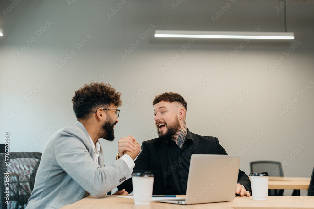 Fototapeta premium Business colleagues arm wrestling in office for friendly competition