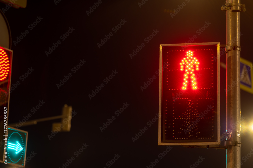 Obraz premium Red pedestrian signal at night in urban setting showing stop for walkers