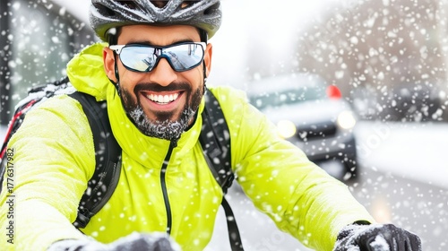 Smiling male cyclist in bright yellow jacket and helmet riding through falling snow on a winter day, active and happy.