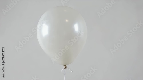 solitary white gas-filled balloon tethered by a string  isolated on a plain white