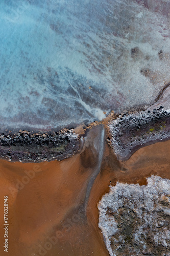 Aerial view of otherworldly landscapes where turquoise waters meet rust-colored earth in a striking, textural contrast, Geothermal Areas, Iceland.
