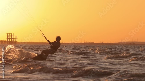Kitesurfer riding waves at golden hour sunset performing dynamic jump with water spray flying creating inspiring moment of extreme sport freedom healthy lifestyle travel adventure ocean horizon beauty