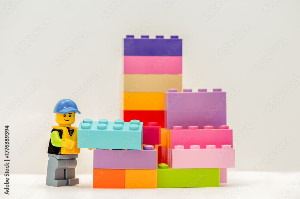 Naklejka premium LEGO Plastic building blocks and construction worker on white background, selective focus