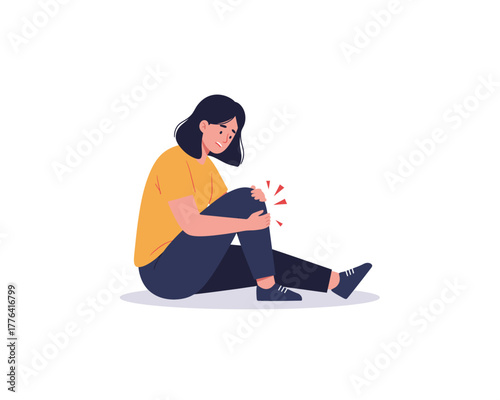 Young woman sitting on the floor holding her knee in pain with a distressed expression on her face