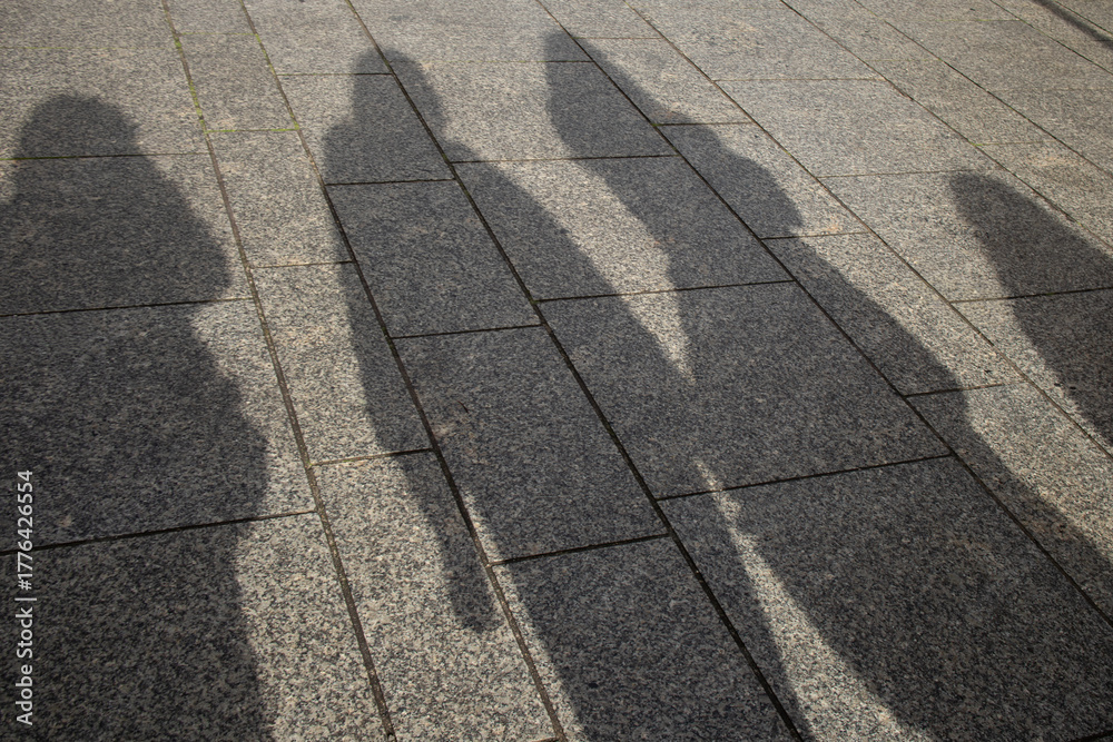 Obraz premium Shadows of People on City Pavement in Sunlight