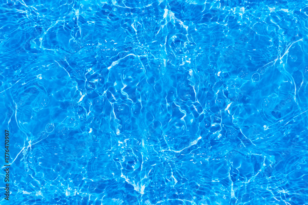 Obraz premium Blue water with ripples on the surface. Defocus blurred transparent blue colored clear calm water surface texture with splashes and bubbles. Water waves with shining pattern texture background.