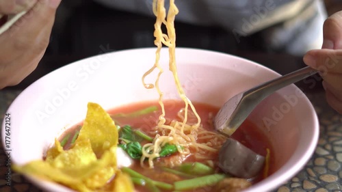 A bowl of Thai Yen Ta Fo noodle soup with pink broth, fish balls, fried wonton, morning glory, and tofu served in a pink bowl. A popular street food dish in Thailand known for its unique sweet and sou