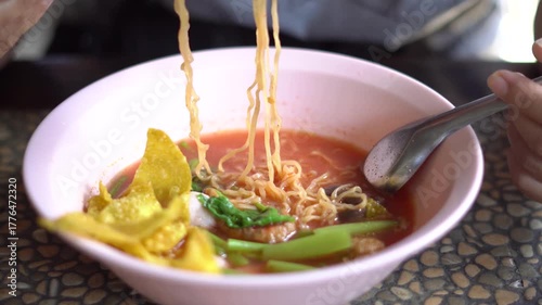 A bowl of Thai Yen Ta Fo noodle soup with pink broth, fish balls, fried wonton, morning glory, and tofu served in a pink bowl. A popular street food dish in Thailand known for its unique sweet and sou