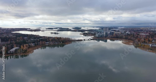 Drone flight over lagoon descending toward modern office buildings in Espoo