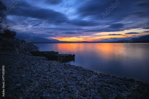 Old fishing boats on a gravel beach under a colorful sky at dusk