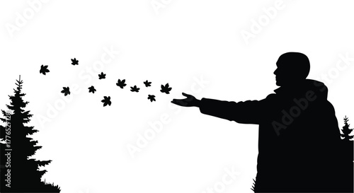 Person releasing leaves into the autumn wind, surrounded by evergreen trees.