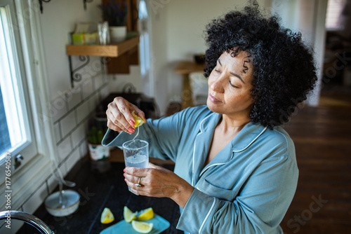Middle aged woman preparing lemon water at home