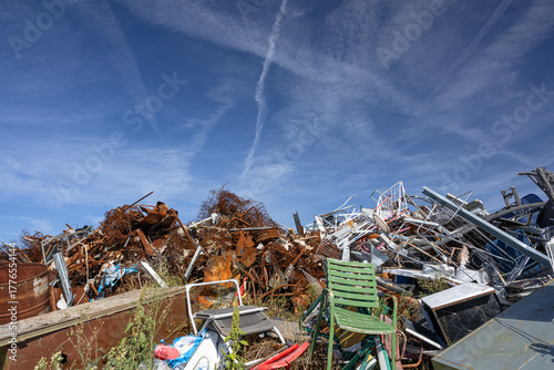 Stacked Pile Of Scrap Metal And Broken Chairs In A Junkyard Under A Bright Blue Sky