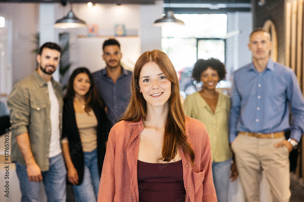 Fototapeta premium Young woman smiling with diverse business team behind her