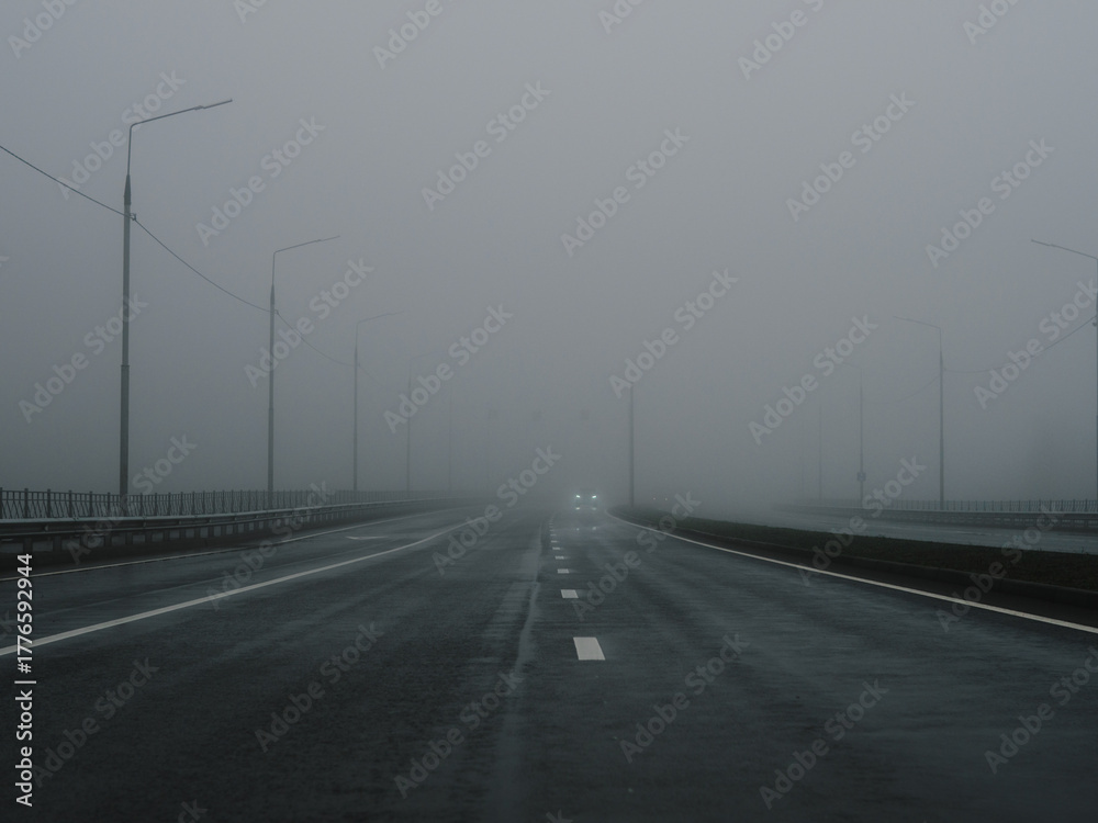 Fototapeta premium Dangerous dense fog on the highway. Poor visibility. Cars in the fog.