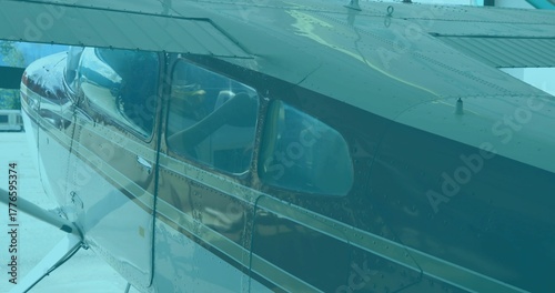 Showing small aircraft fuselage on airport ramp, with cabin windows and wing support struts