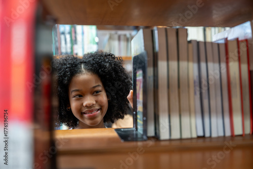 African American young student girl finding book on the bookshelf in school library. Learning, knowledge, and education concepts.