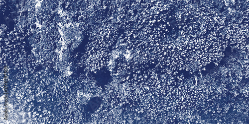 Close-up textured background of dark blue and white granular particles with irregular dark shadows suggesting a rough, gritty surface or abstract material