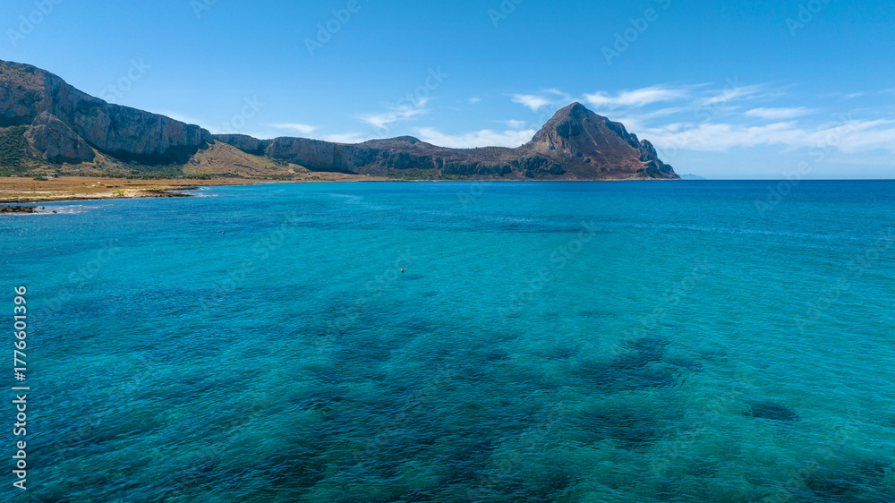 Fototapeta premium Panorama of Cofano Mount located in the province of Trapani, Sicily, Italy. A mountain in the background and the turquoise sea in the foreground.