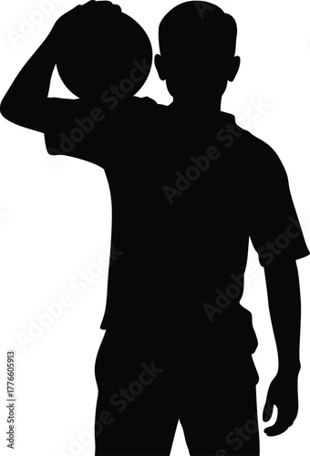 Silhouette of a young boy holding a basketball over his shoulder ready to play