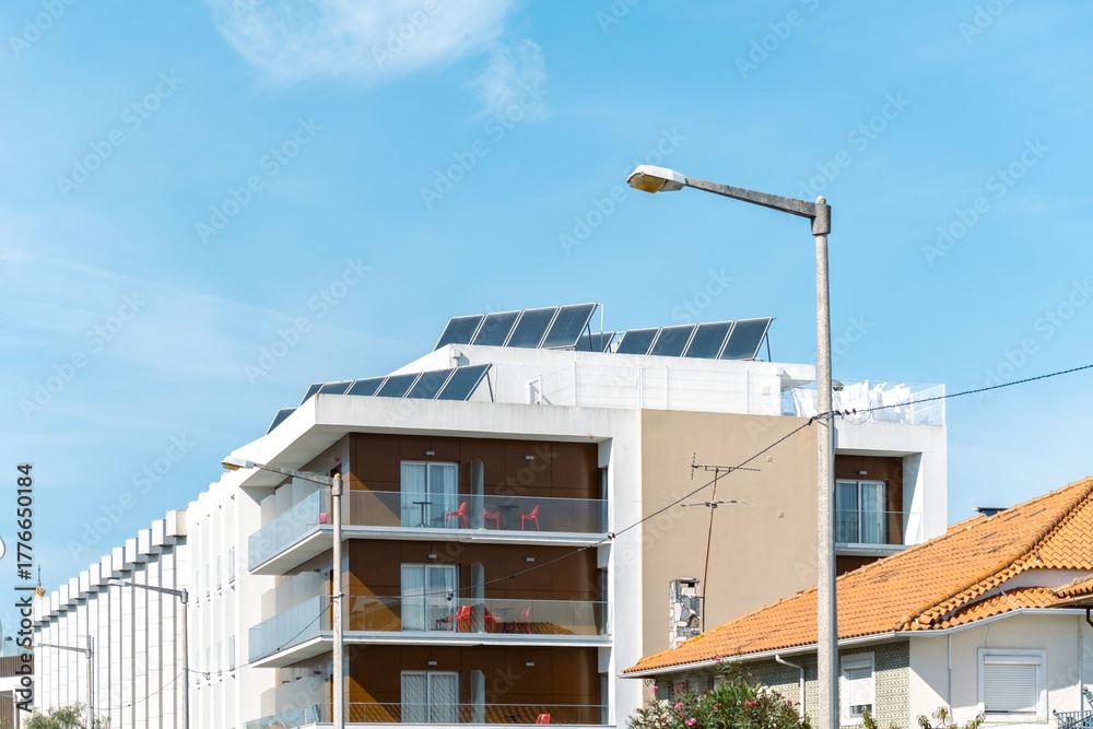 Obraz premium Modern building with solar panels and balconies under blue sky in a sunny neighborhood