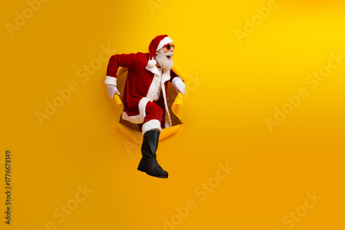 Santa Claus bursting through a yellow background showcasing festive cheer and holiday magic in a creative and charismatic pose